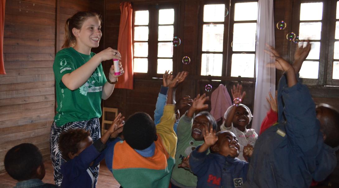 Voluntaria jugando con niños pequeños. En un voluntariado para enseñar inglés adquirirás experiencia mientras ayudas a niños pequeños a mejorar sus habilidades.